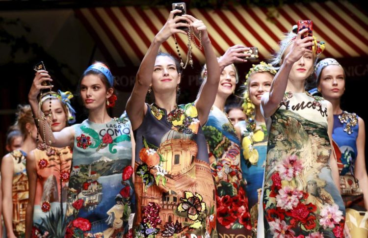 Models take selfie with mobile phones during the parade at the end of the Dolce & Gabbana Spring/Summer 2016 collection during Milan Fashion Week