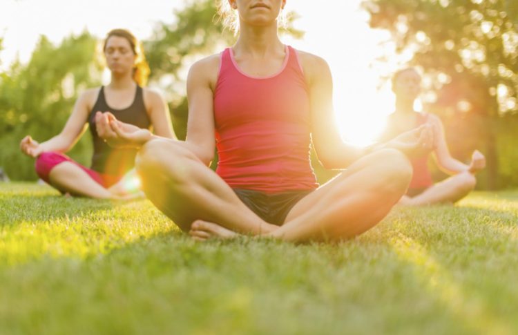 group of 3 women doing yoga in nature